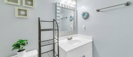 Une salle de bain avec un lavabo blanc, un miroir, un porte-serviettes et des toilettes.
