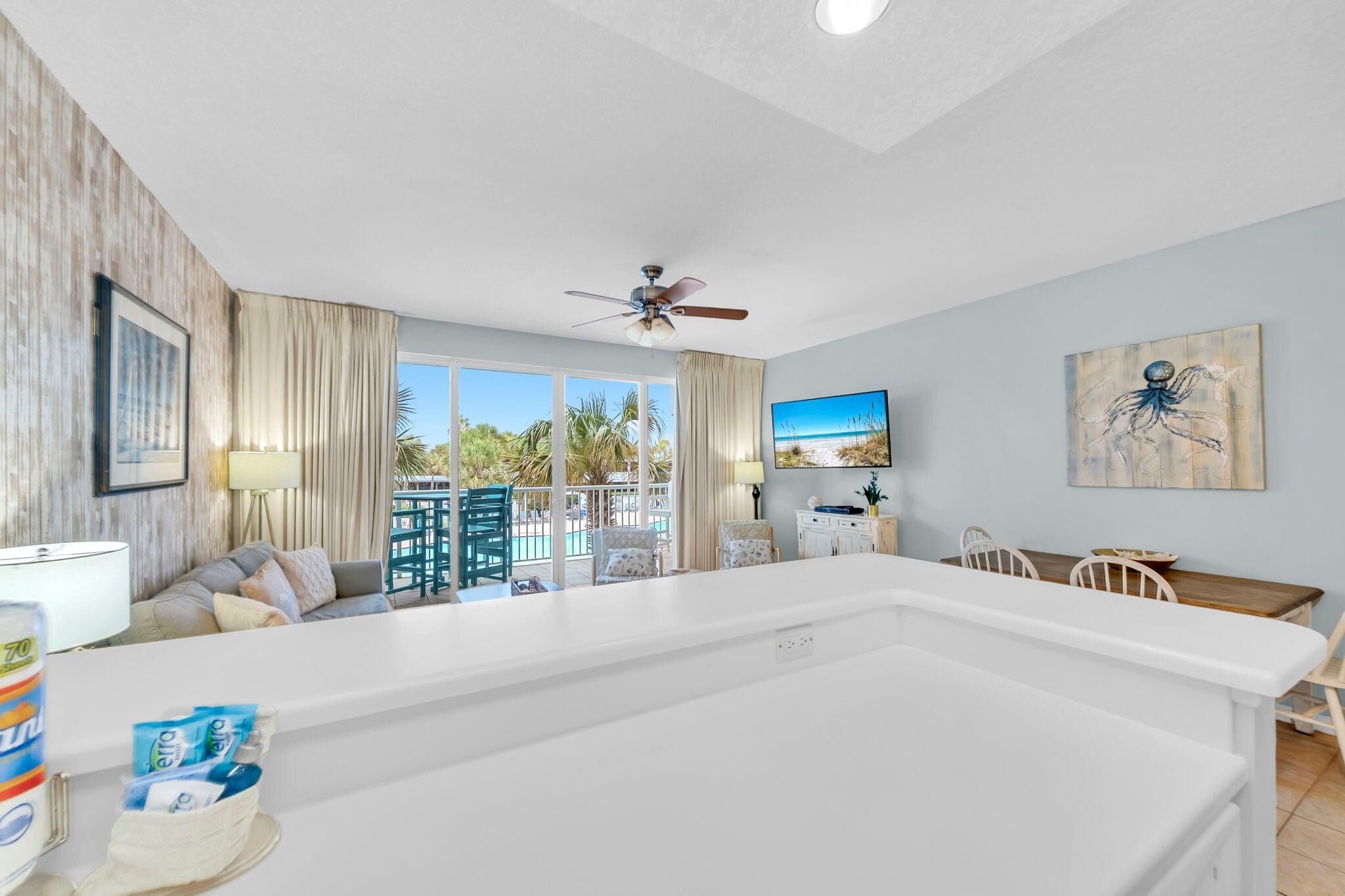 A spacious living area with a large white pool, a ceiling fan, and a view of the outdoors.