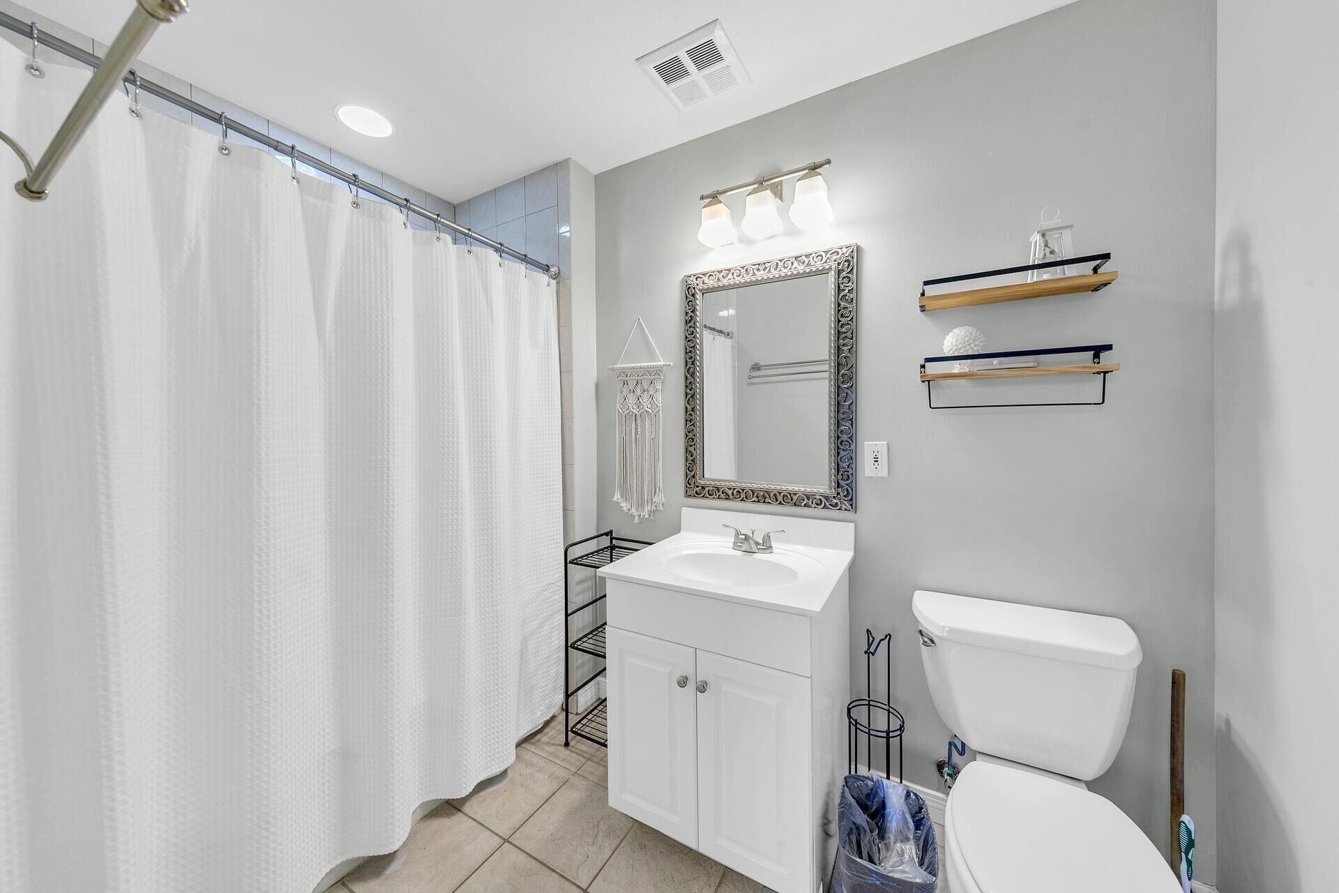 A bathroom with a shower, toilet, sink, and vanity.