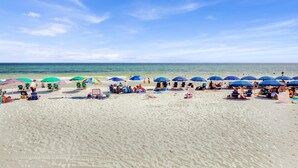 A beach with multiple umbrellas and beach chairs, a sign indicating no tents allowed, and a clear view of the ocean. - Destin West Gulfside 304 (Fort Walton Beach)
