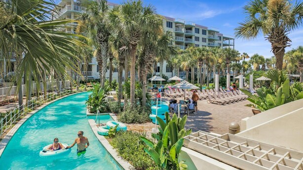 A resort pool area with a clear blue pool, lounge chairs, and palm trees. - Destin West Gulfside 304 (Fort Walton Beach)