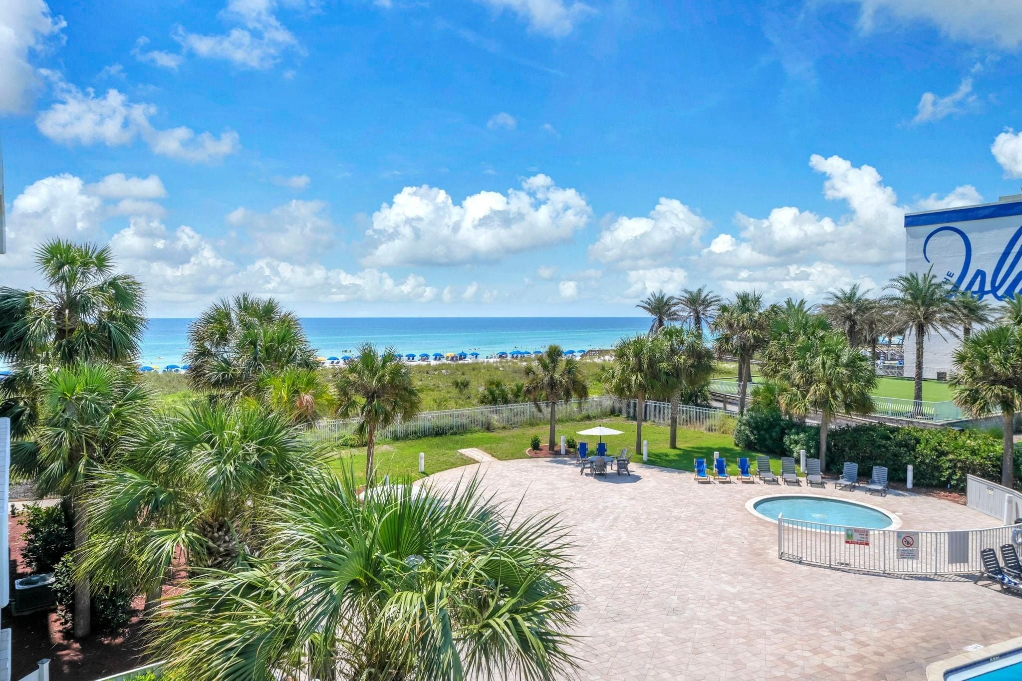 A pool area with lounge chairs, a swimming pool, and a view of the beach and ocean.