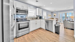 Una cocina moderna con electrodomésticos de acero inoxidable, armarios blancos y suelo de madera.
