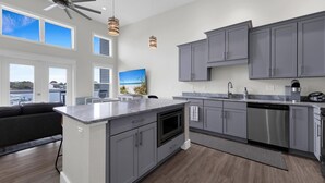 Una cocina moderna con armarios grises, una isla grande y vistas al puerto deportivo.