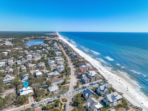 An aerial view of a coastal residential area with houses along the beach, a clear blue sky, and a calm sea. - Cloud Nine (Santa Rosa Beach)