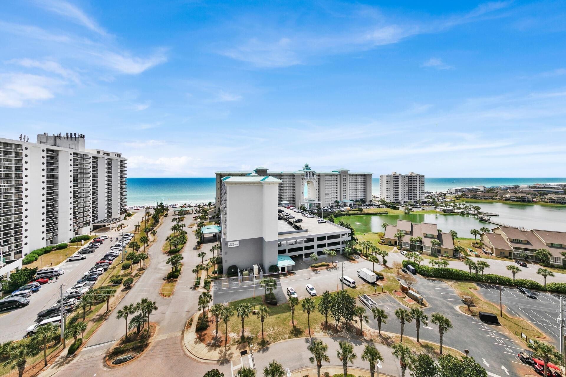Um hotel moderno com pátio central, estacionamento e vista para a praia e o oceano.