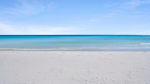 A beach with clear blue water and a sandy shore. - St. Croix 206 at Silver Shells (Destin)