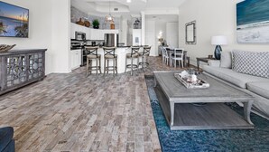 A spacious living area with a kitchen, dining area, and a large window with a view of the ocean. - St. Croix 206 at Silver Shells (Destin)
