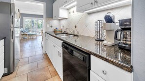 Eine moderne Küche mit weißen Schränken, einem Edelstahl-Kühlschrank, einer Spülmaschine und einer Kaffeemaschine.