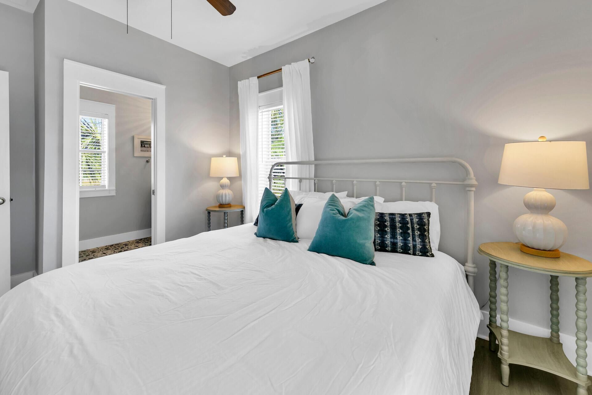 A bedroom with a bed, two bedside tables, a window with curtains, and a ceiling fan.