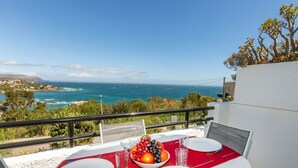 A table set for two with a red tablecloth, white plates, and a bowl of fruit on a balcony overlooking the sea. - Apartment Aloes by Interhome (Llançà)