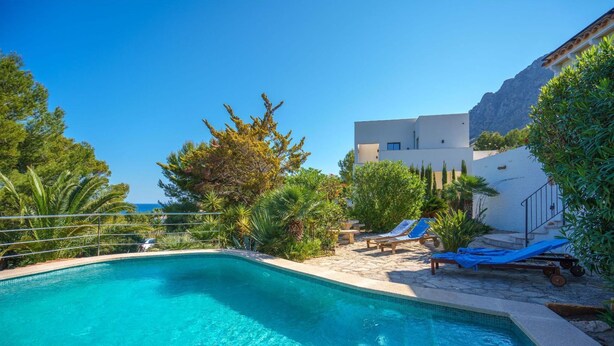 A clear blue swimming pool with lounge chairs and a view of a mountain in the background. - Pinomar by Interhome (Colònia Sant Pere)