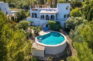 Une vaste villa moderne dotée d’une piscine, entourée d’une végétation luxuriante et d’un jardin bien entretenu.