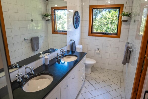 Un baño moderno con dos lavamanos, un inodoro y una ventana.