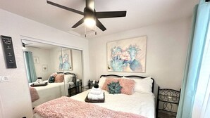 A bedroom with a bed, a ceiling fan, a mirror, a painting, and a window with curtains. - Lake View • Hot Tub • RV/Boat Parking • Fire Pit (Lake Havasu City)