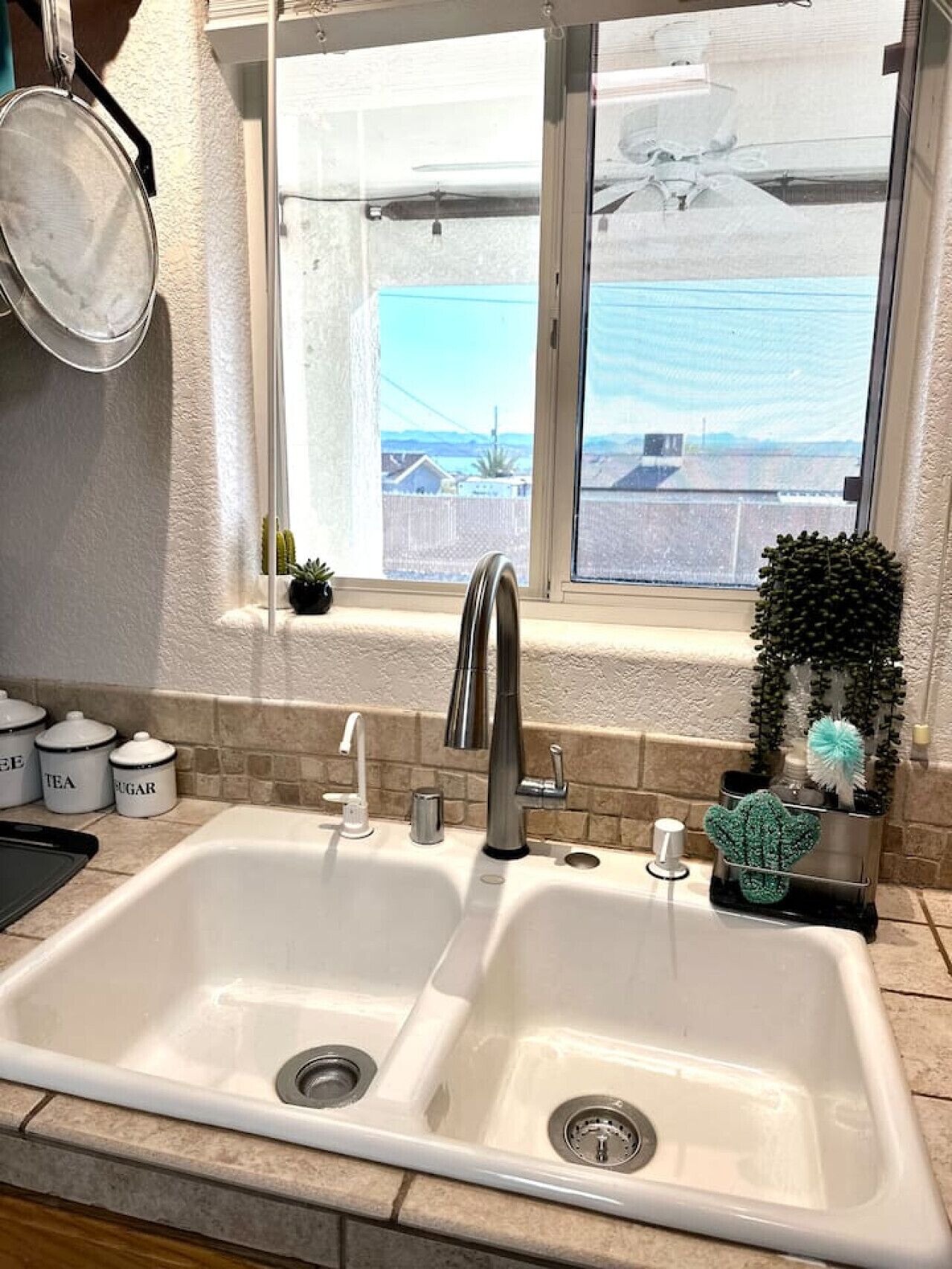 Una cocina con un lavamanos doble, una ventana con vistas y utensilios de cocina sobre la encimera.
