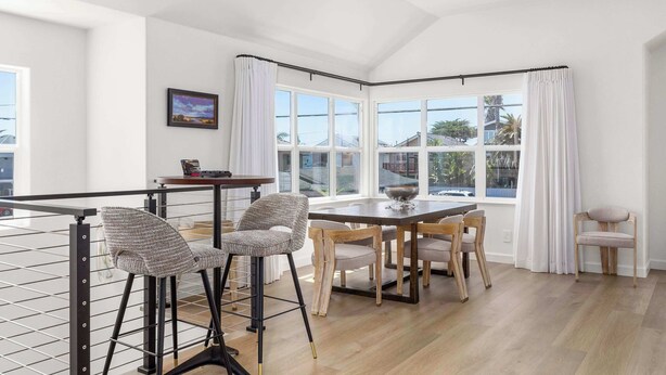Un comedor con una mesa y sillas, una ventana con cortinas y un cuadro en la pared.