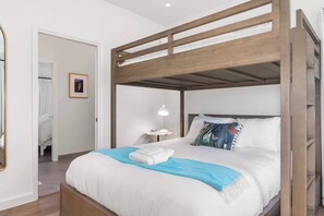 Una cama individual con estructura de madera, una mesita de noche con lámpara y un cuadro en la pared.
