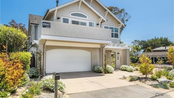 A two-story house with a garage, a covered front porch, and a landscaped garden.