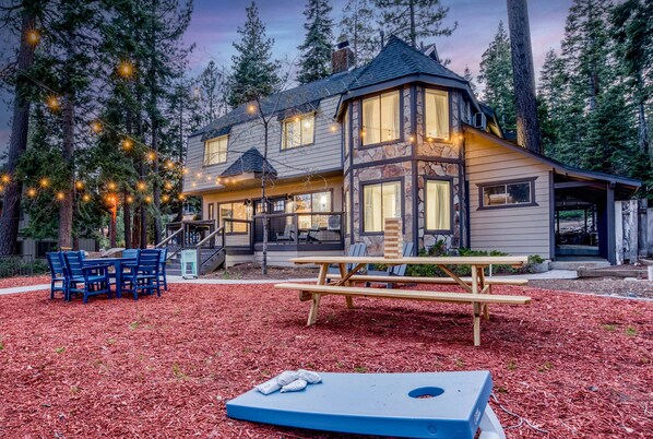 A lodge with a stone facade, large windows, and a deck area with picnic tables and chairs.