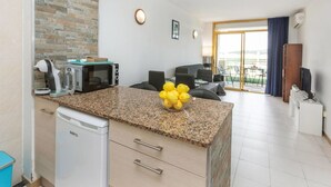 A modern kitchen with granite countertops, a coffee machine, a microwave, and a dishwasher. There is a dining area with a table and chairs, and a balcony with a view. - Lovely apartment for 4 people with pool, WIFI, A/C, TV and terrace (Salou)