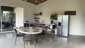 A modern kitchen with a round dining table, grey chairs, and a stainless steel refrigerator. - Don Cidales House (Pocosol)