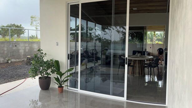 A modern outdoor patio with a glass door leading to an indoor area. - Don Cidales House (Pocosol)