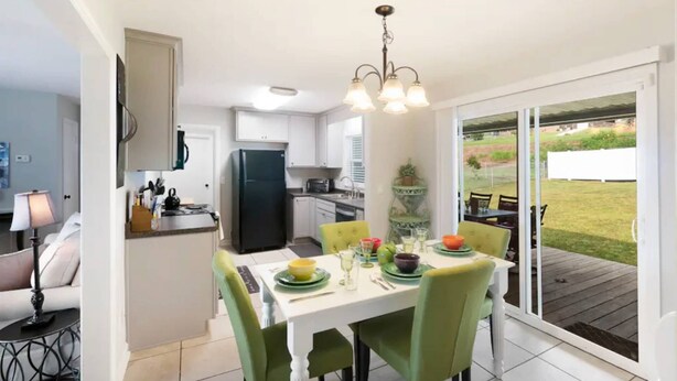 A modern kitchen with a dining area, a black refrigerator, and a table set for four with chairs.