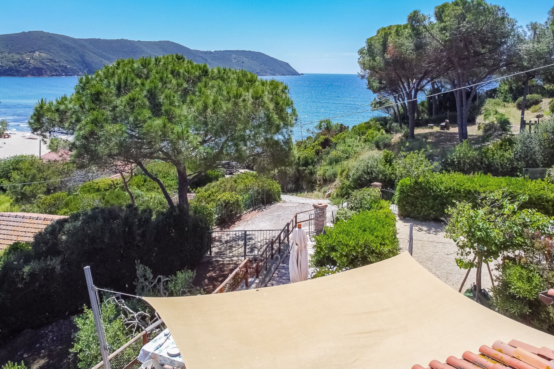 Paesaggio costiero con spiaggia, alberi e cielo sereno.