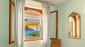 Ein Zimmer mit einem großen Fenster, einem Spiegel und einem Stuhl.