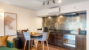 A modern kitchen with a dining area, a map on the wall, and a sofa. - The Nugget-Free Parking-Direct Lake Access (Queenstown)