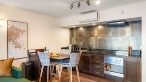A modern kitchen with a dining area, a map on the wall, and a sofa.