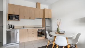 Une cuisine moderne dotée de meubles en bois, d’un four à micro-ondes, d’un réfrigérateur, d’un lave-vaisselle et d’un coin repas avec une table et des chaises.