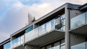 Un bâtiment moderne doté de nombreux balcons, de grandes fenêtres et surplombant un ciel dégagé.