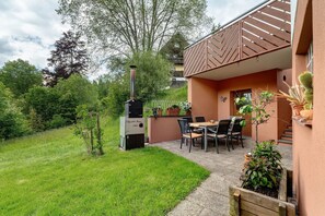 A patio with a grill, outdoor seating, and potted plants.