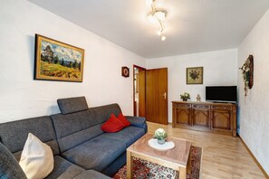 A living room with a sofa, a coffee table, a television, and a cabinet.