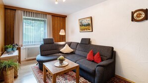 Un salon avec un canapé, une petite table, une lampe, une horloge et un tableau accroché au mur.