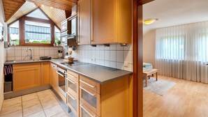 Una cocina con armarios de madera, una encimera y un ventanal con persianas.