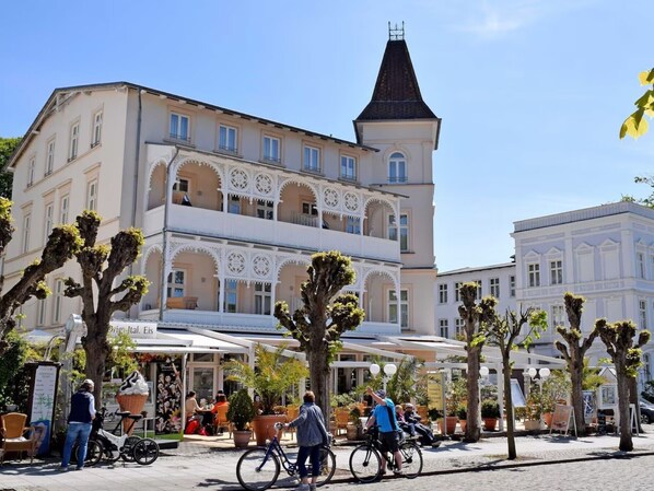 A building with a balcony, potted plants, and outdoor seating.