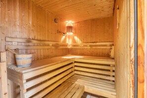 Eine Holzsauna mit Bänken, einem Eimer und einer Lampe.