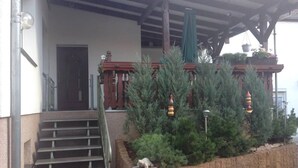 A covered outdoor area with a set of stairs leading to a door, surrounded by greenery and decorative elements. - Apartment 'Ruhiges Nest Mit Sauna Und Garten' with Shared Garden and Wi-Fi (Jessen (Elster))