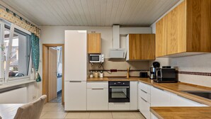 Una cocina compacta con armarios blancos, un microondas, un horno y encimeras de madera.