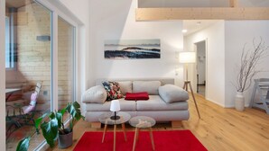 A modern living room with a sofa, a glass coffee table, a red rug, and a painting on the wall. - Apartment 'Hedi' with Mountain View, Balcony and Wi-Fi (Feldberg (Schwarzwald))