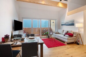 A modern living room with a dining area, a sofa, a TV, and a large window. - Apartment 'Hedi' with Mountain View, Balcony and Wi-Fi (Feldberg (Schwarzwald))
