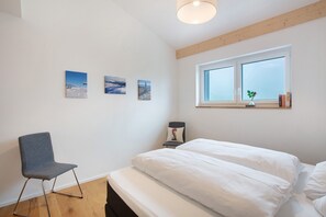Une chambre à coucher comprenant un lit, une chaise et trois tableaux accrochés au mur.