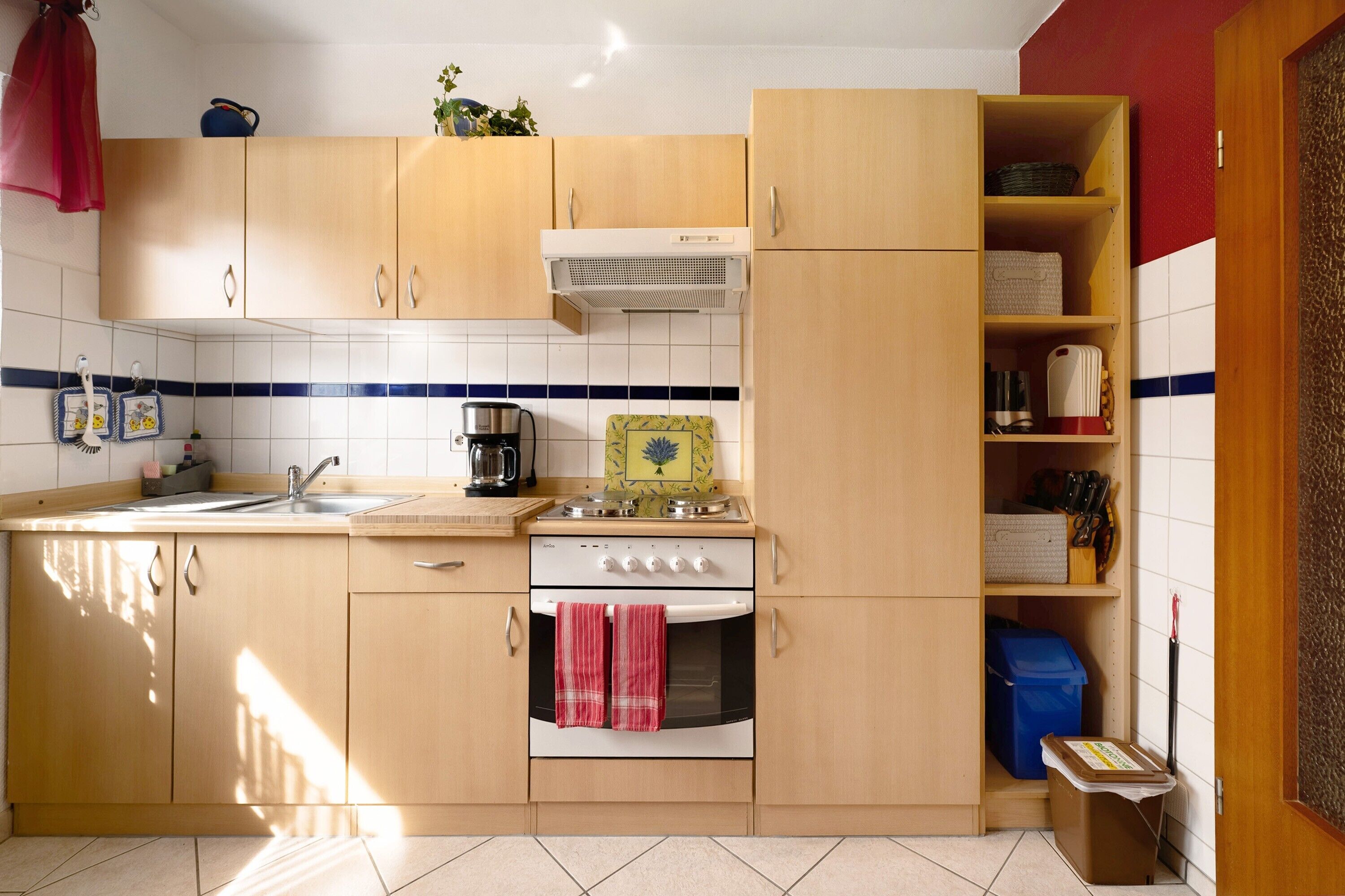 Una cocina con armarios de madera, estufa, fregadero y salpicadero de azulejos.