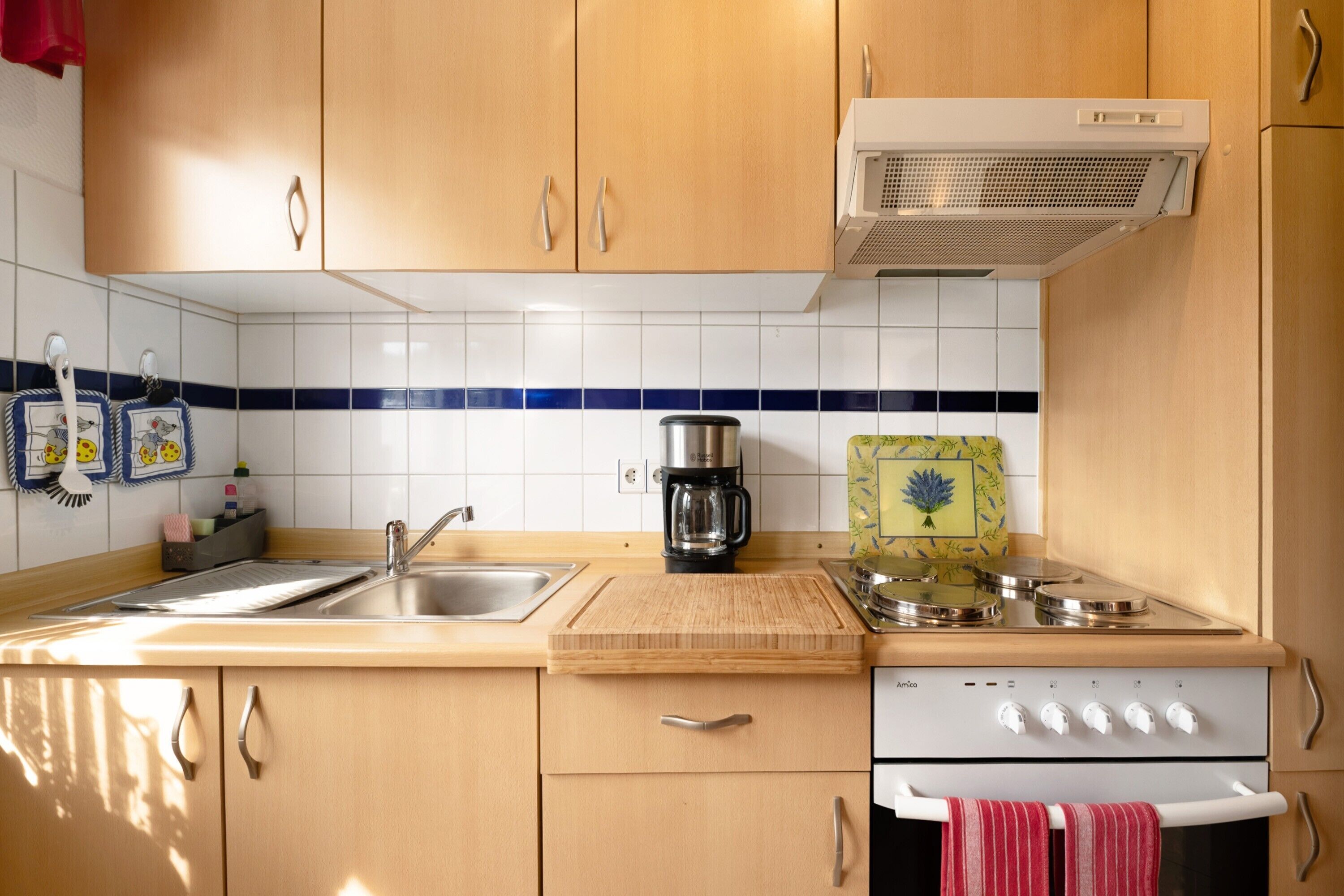 Une cuisine avec des meubles de rangement en bois, un évier, une cuisinière et une machine à café.
