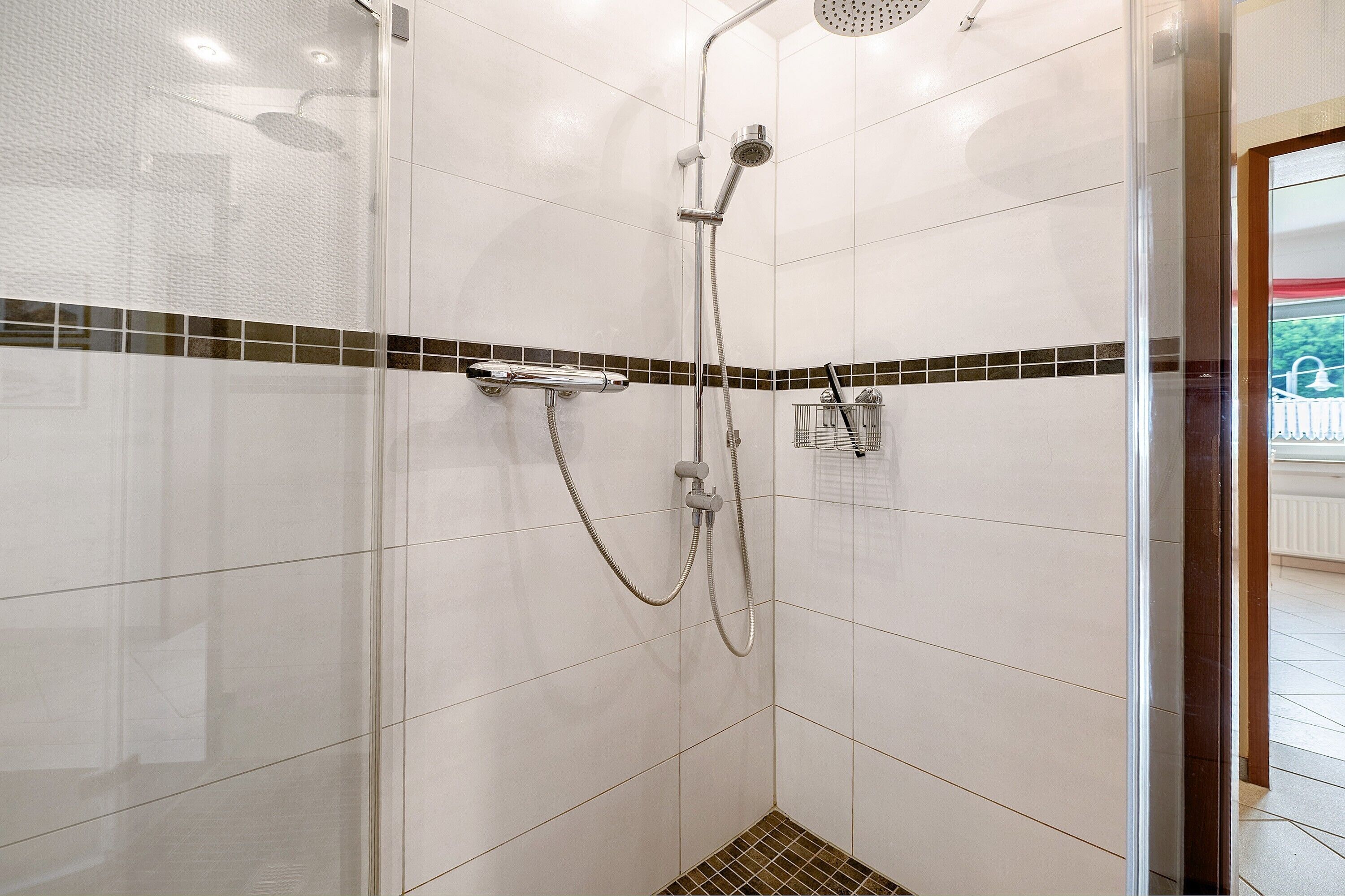 En bruser med håndbruser, vægmonteret armatur og kontrolpanel.