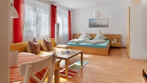 Ein Zimmer mit einem Bett, einem Schlafsofa, einem Esstisch und einem Stuhl.
