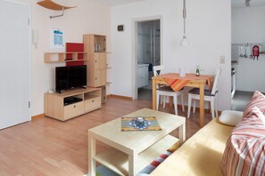A modern living room with a TV, wooden furniture, a dining table, and a sofa. - Studio Apartment 'Ferienwohnung Zur Schauinslandbahn' with Mountain View, Private Terrace and Wi-Fi (Horben)